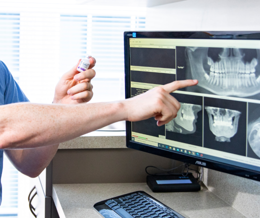 Doctor holding an Exparel vial while pointing to a wisdom teeth x-ray on a screen.