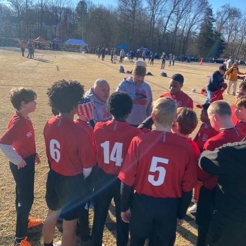 Dr. Cook in a group huddle with the rugby team on the field.