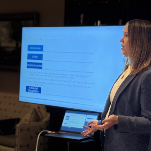 Dr. Hailger presenting a presentation slide during a lecture, with the slide visible on a screen behind her.