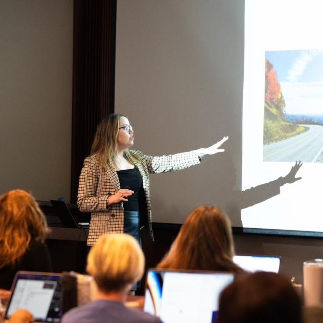 Dr. Hailger pointing to a presentation slide on a screen during a lecture.