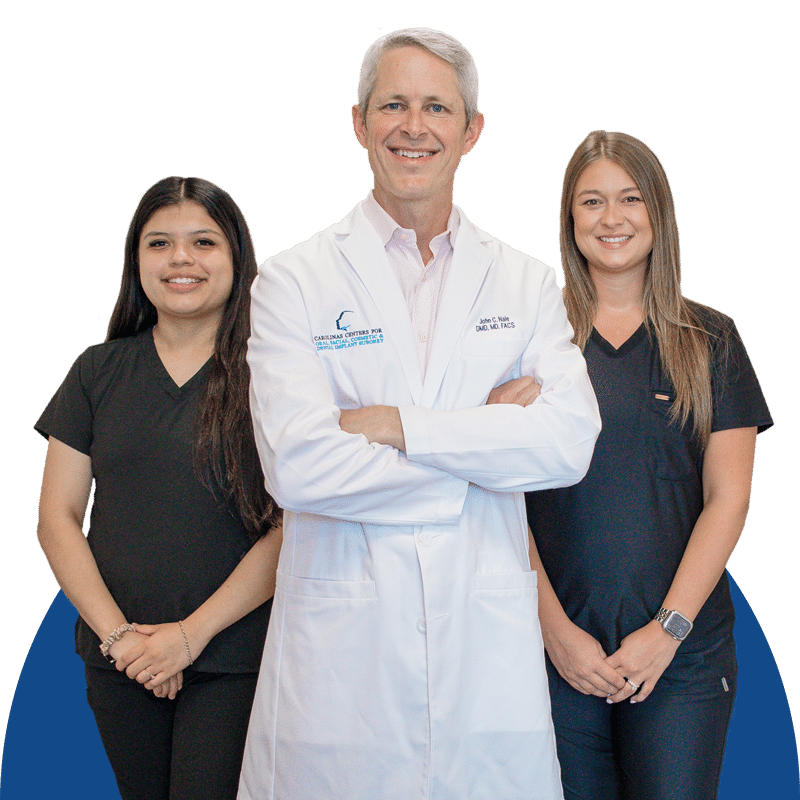 Three people stand against a blue background; the central person in a white coat, flanked by two others in black attire.