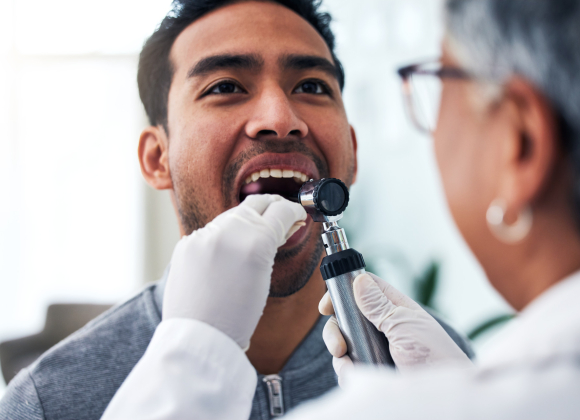 A close up of a doctor give a man an oral exam.